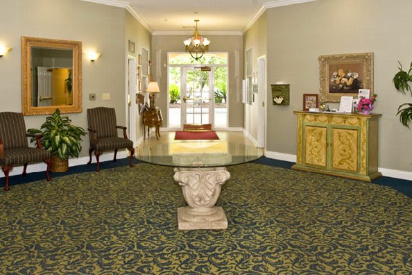 A well-decorated lobby area featuring a central glass table, a chandelier, and traditional furnishings.