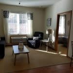 A cozy living room with a comfortable chair, coffee table, and large window letting in natural light.
