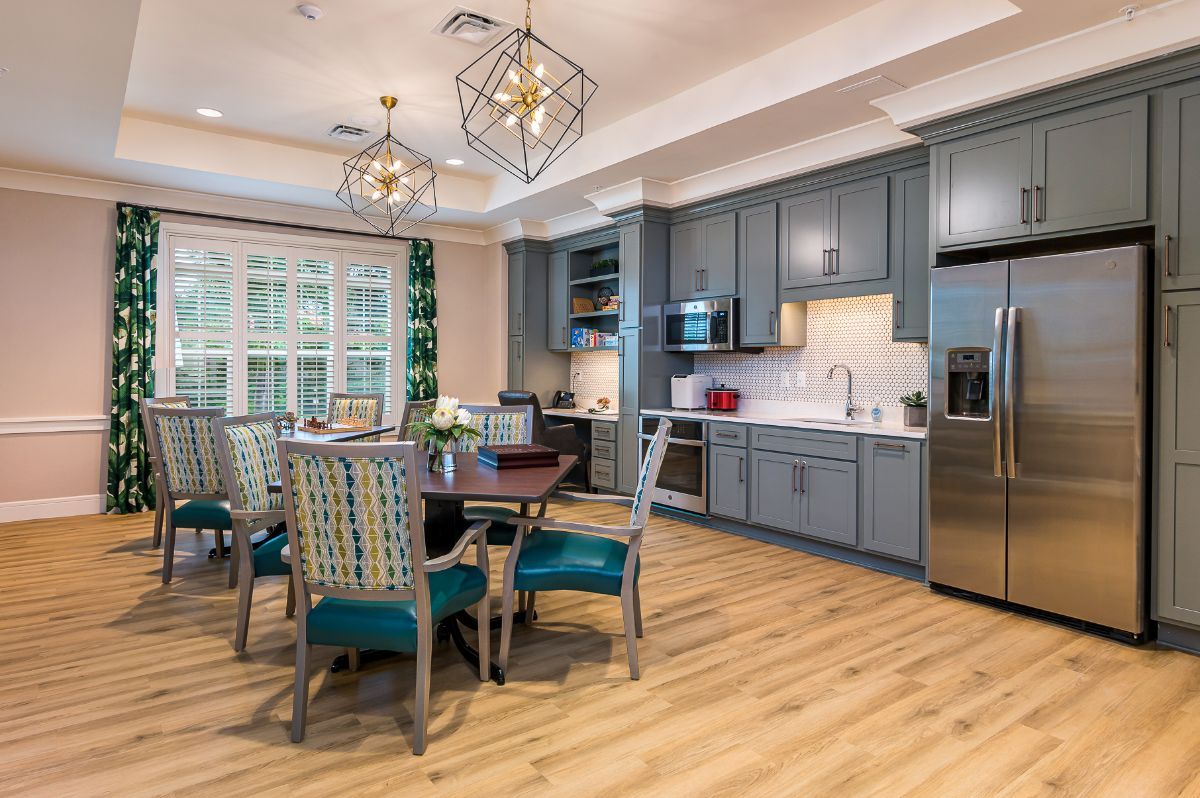 A modern kitchen with a dining area featuring wood flooring, blue cabinets, and stylish chandeliers.