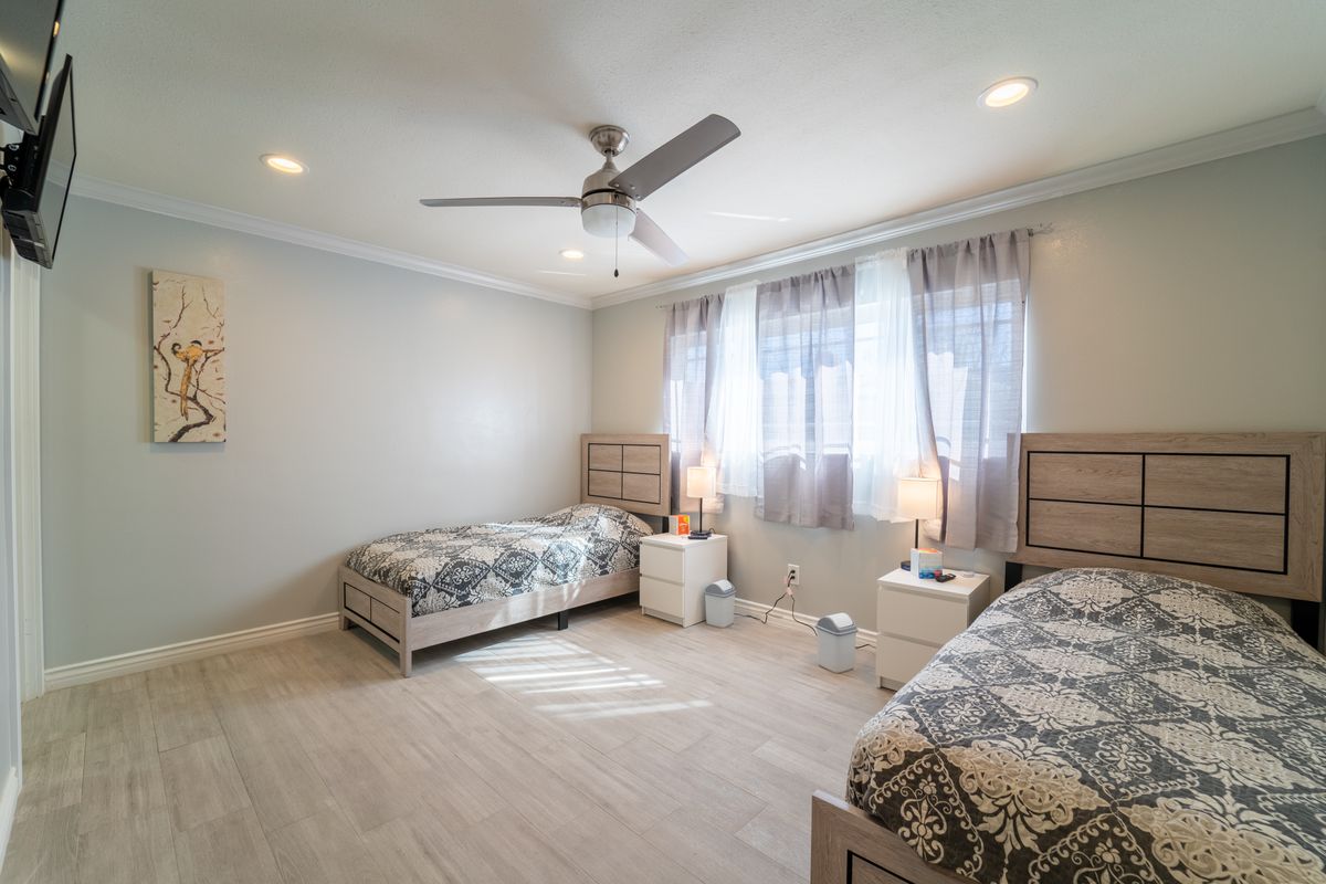 A modern bedroom with two twin beds, ample natural light, and stylish decor.