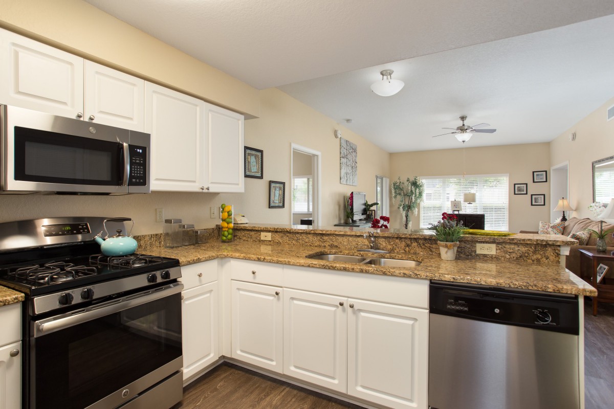 A modern kitchen with white cabinets, stainless steel appliances, and granite countertops.