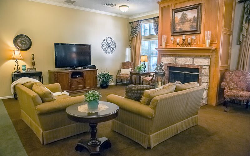 A cozy living room featuring a fireplace, sofas, and a television.