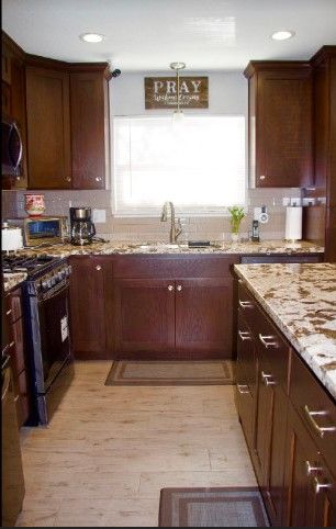 A modern kitchen with wooden cabinets and granite countertops featuring a stove, coffee maker, and sink.