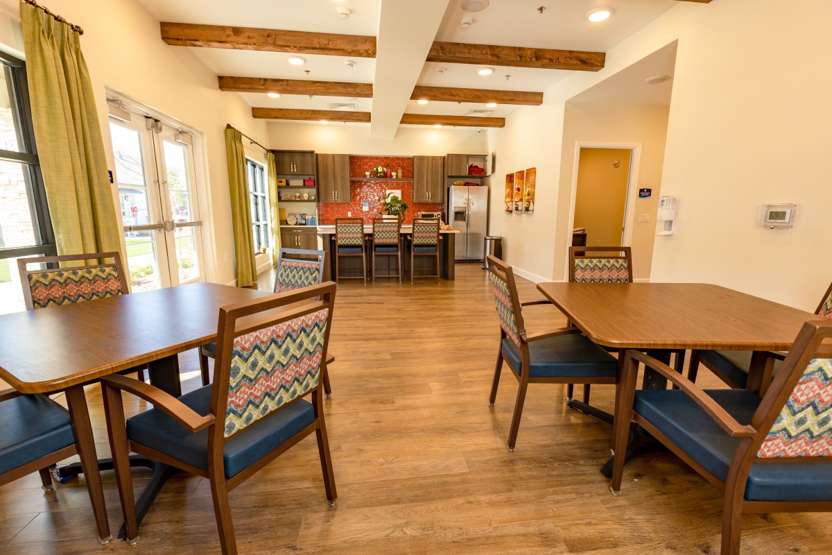 A modern kitchen and dining area featuring wooden floors, tables, and chairs.