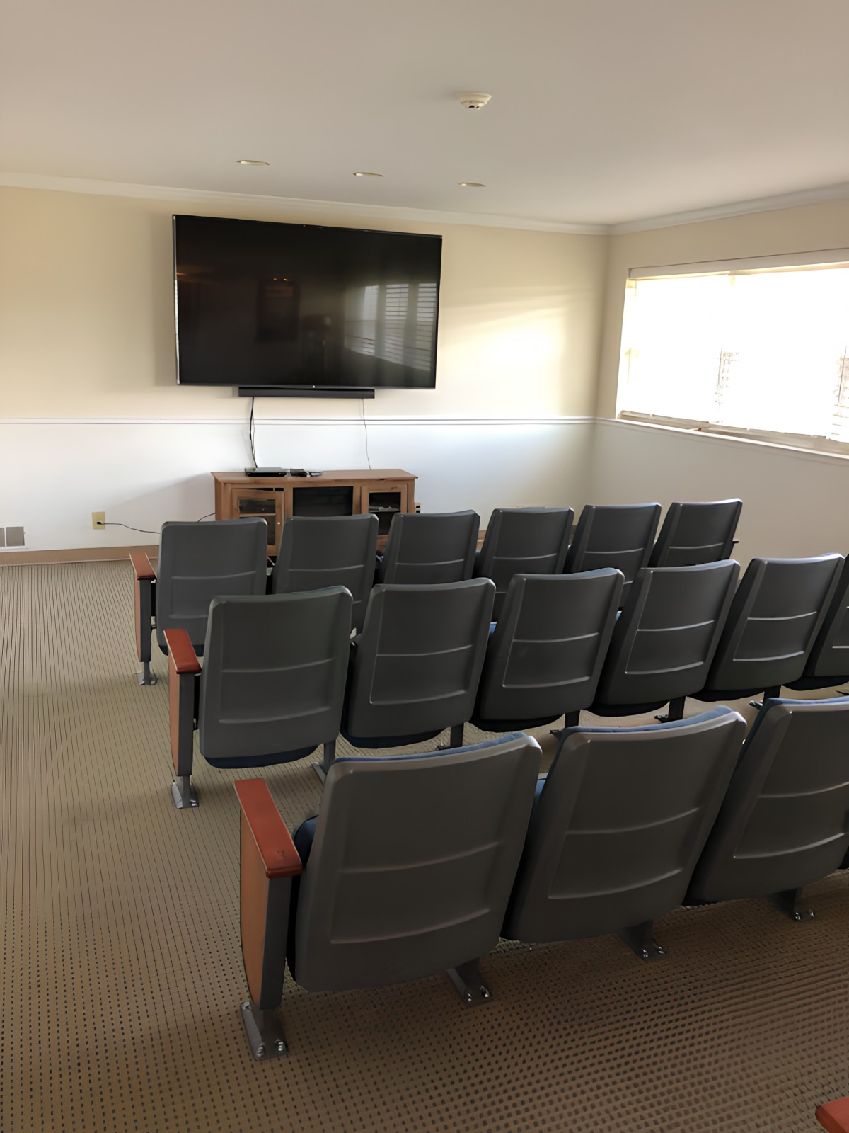 A small conference or classroom setup with multiple rows of chairs facing a large television screen.