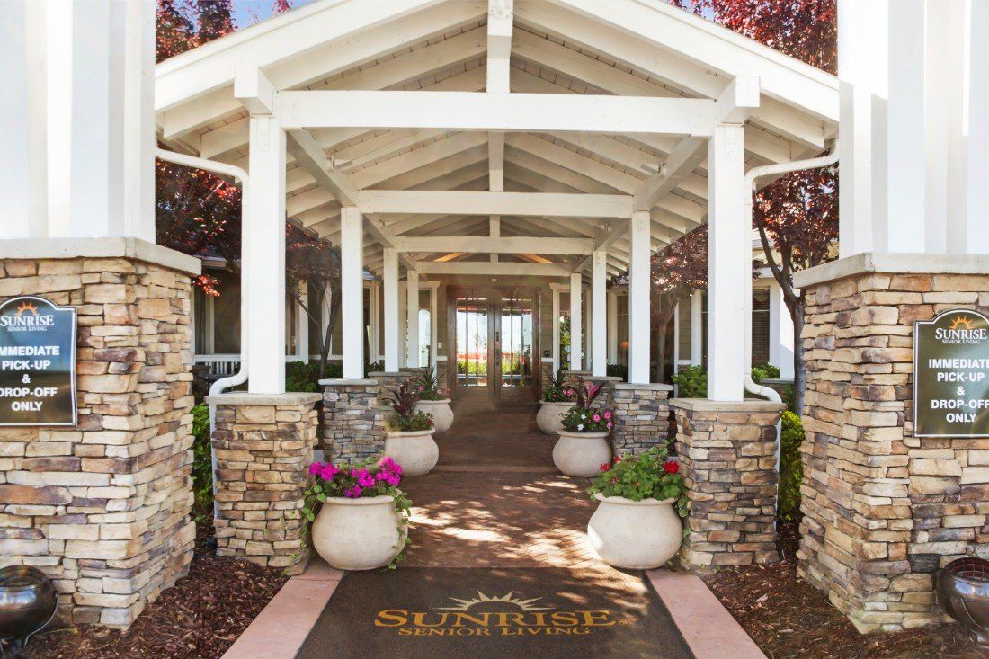 A beautifully designed entrance with a pathway lined by columns and potted plants.