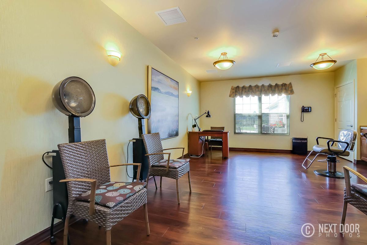 A spacious salon interior with chairs and hair dryers, featuring wood flooring and ample natural light.