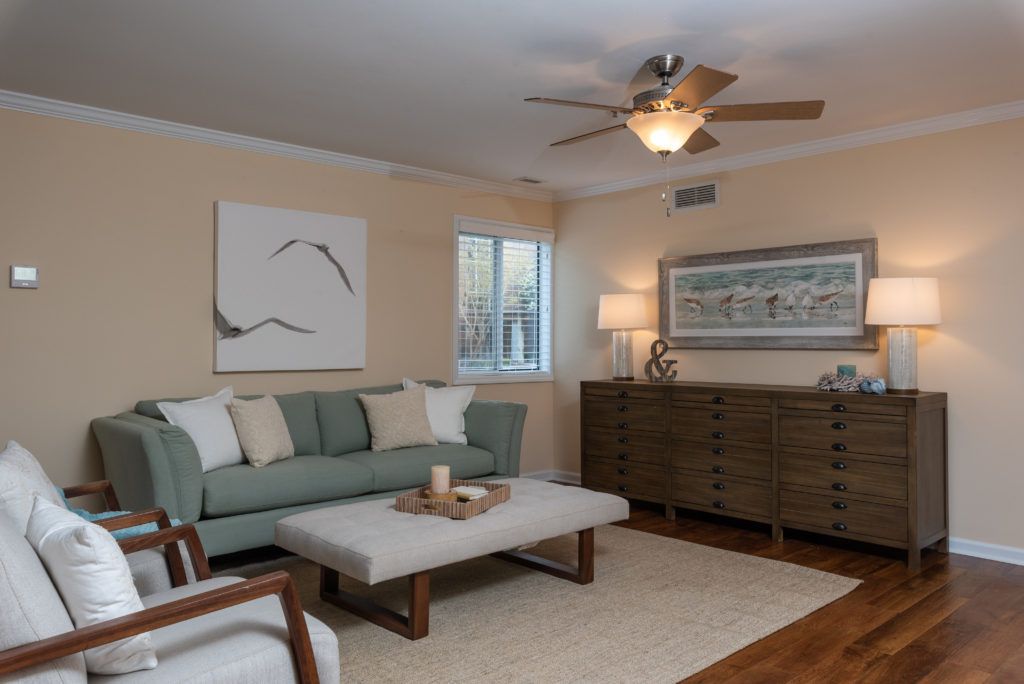 A cozy living room with modern decor, featuring a green sofa, wooden furniture, and abstract artwork.