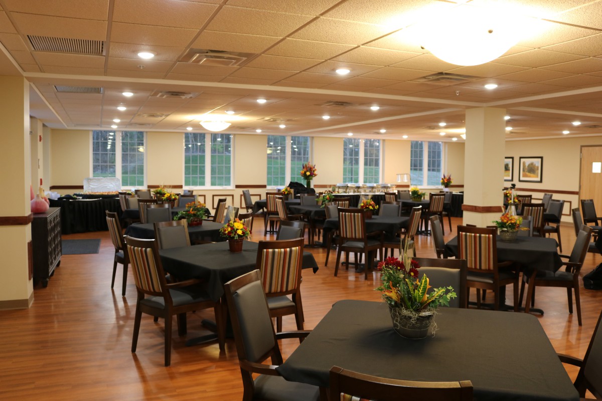 An inviting dining area with neatly arranged tables and chairs, complemented by soft lighting and decorative plants.
