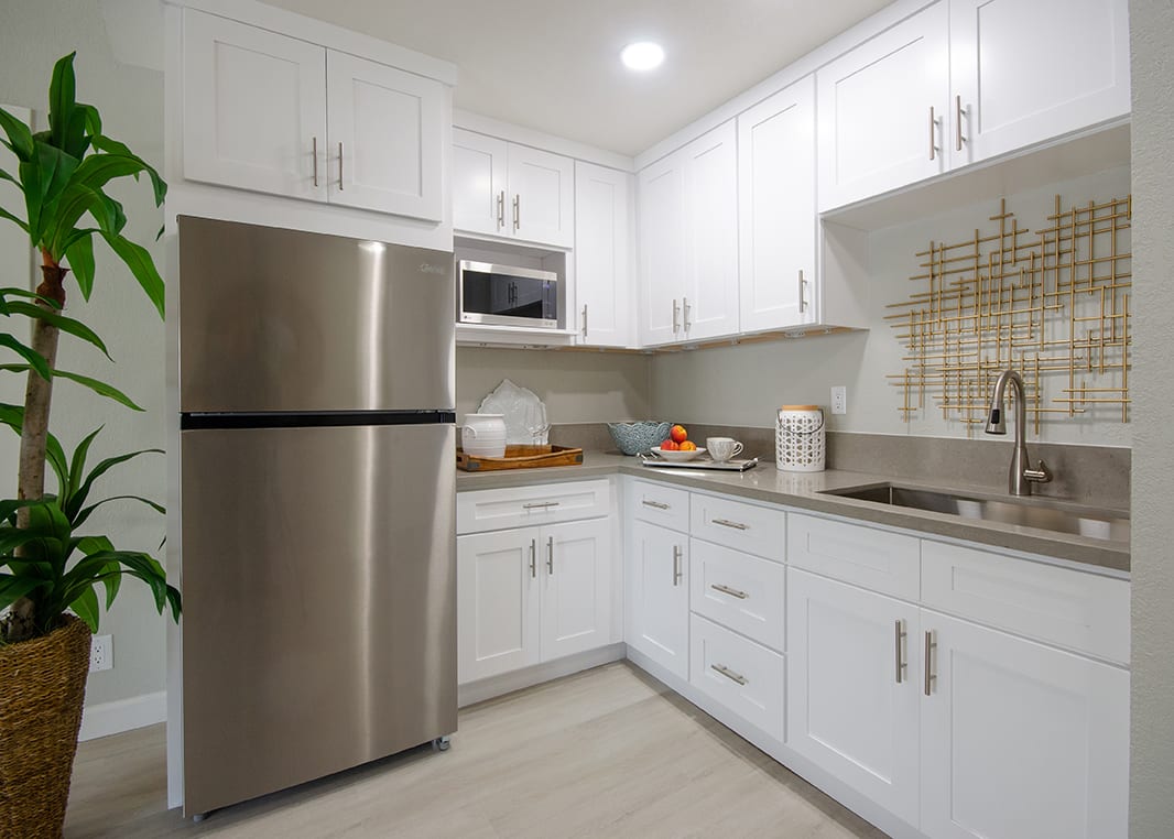A modern kitchen with white cabinets and stainless steel appliances in a compact layout.