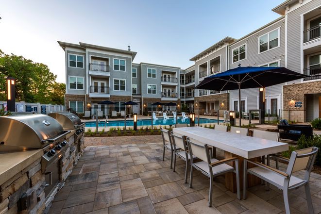 A modern apartment complex featuring a swimming pool and outdoor seating area.