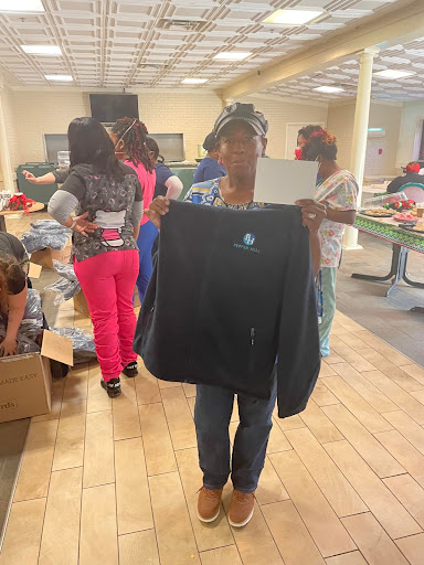 A participant proudly holds up a newly received jacket during a community clothing donation event.