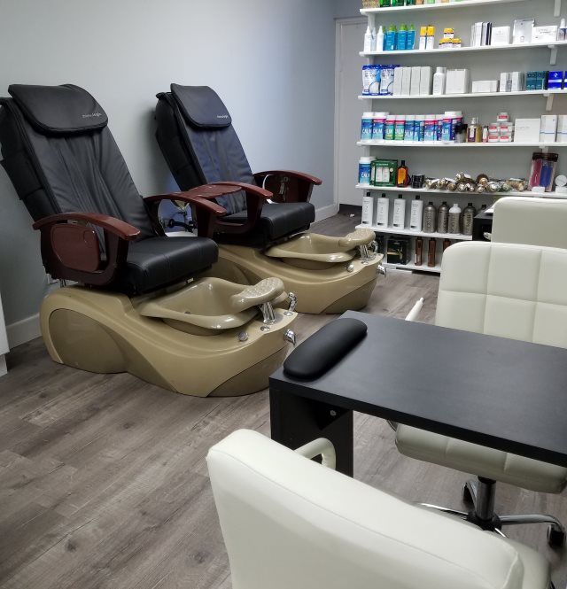 A cozy nail salon featuring pedicure chairs and a manicure station, with shelves stocked with beauty products.