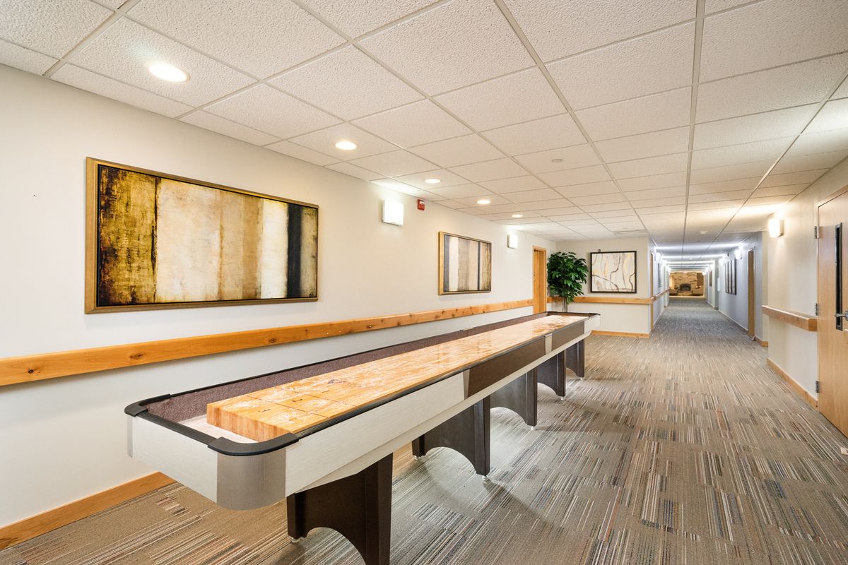 A modern hallway features a shuffleboard table and contemporary artwork on the walls.