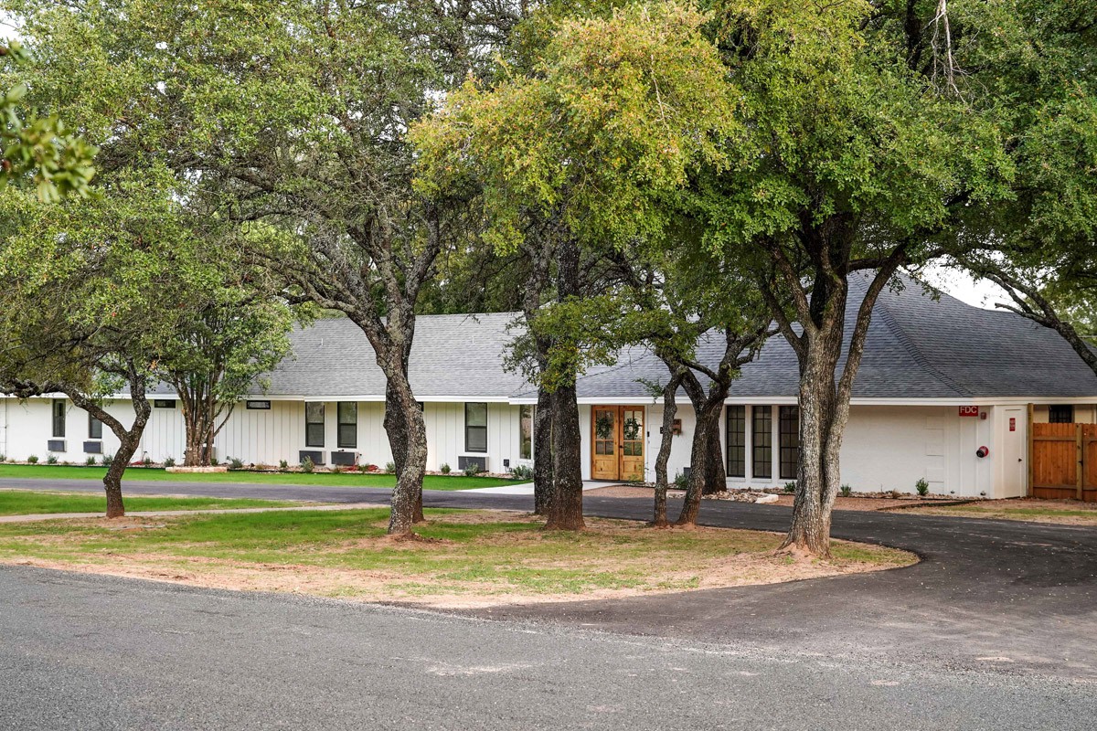 A suburban house surrounded by trees with a driveway.