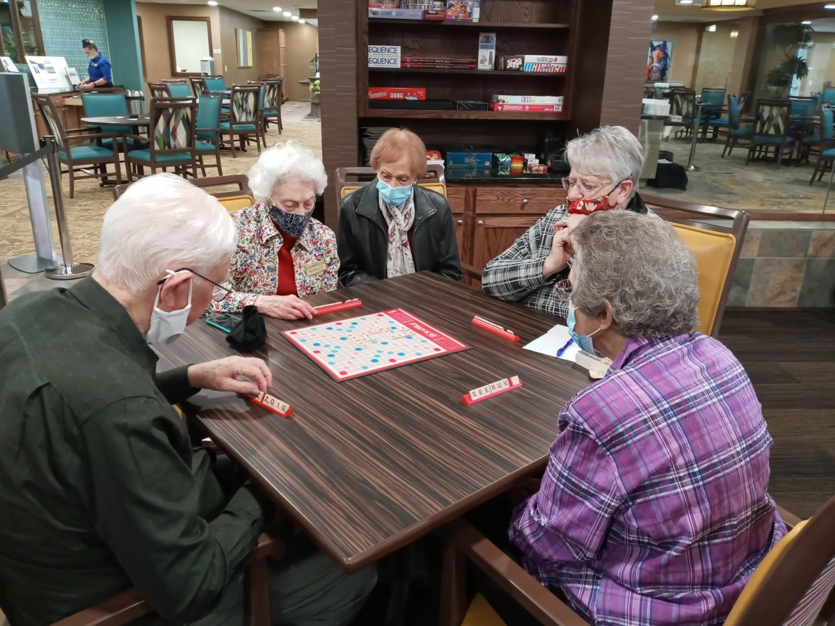 A group of seniors playing a game of Scrabble together indoors.