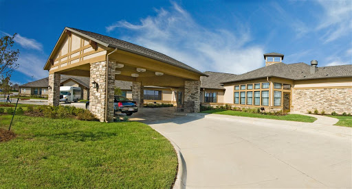 A modern residential building with a spacious driveway and green surroundings.