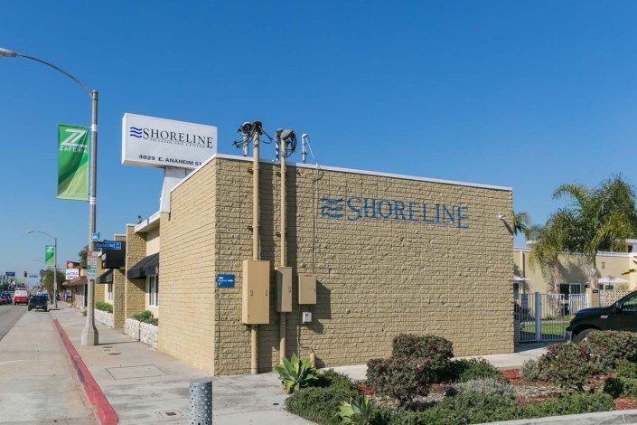 Exterior view of the Shoreline Motel with a visible sign and surrounding landscape.