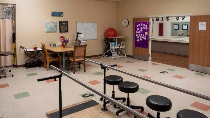 A rehabilitation room equipped with parallel bars and various therapy tools.