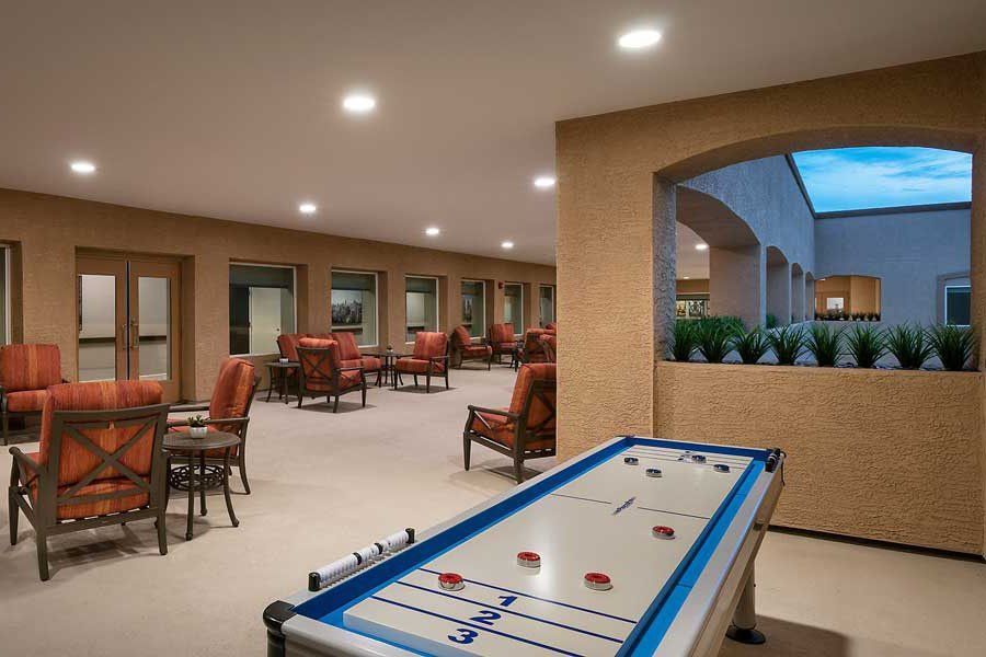 A spacious indoor recreation area featuring a shuffleboard table and comfortable seating.