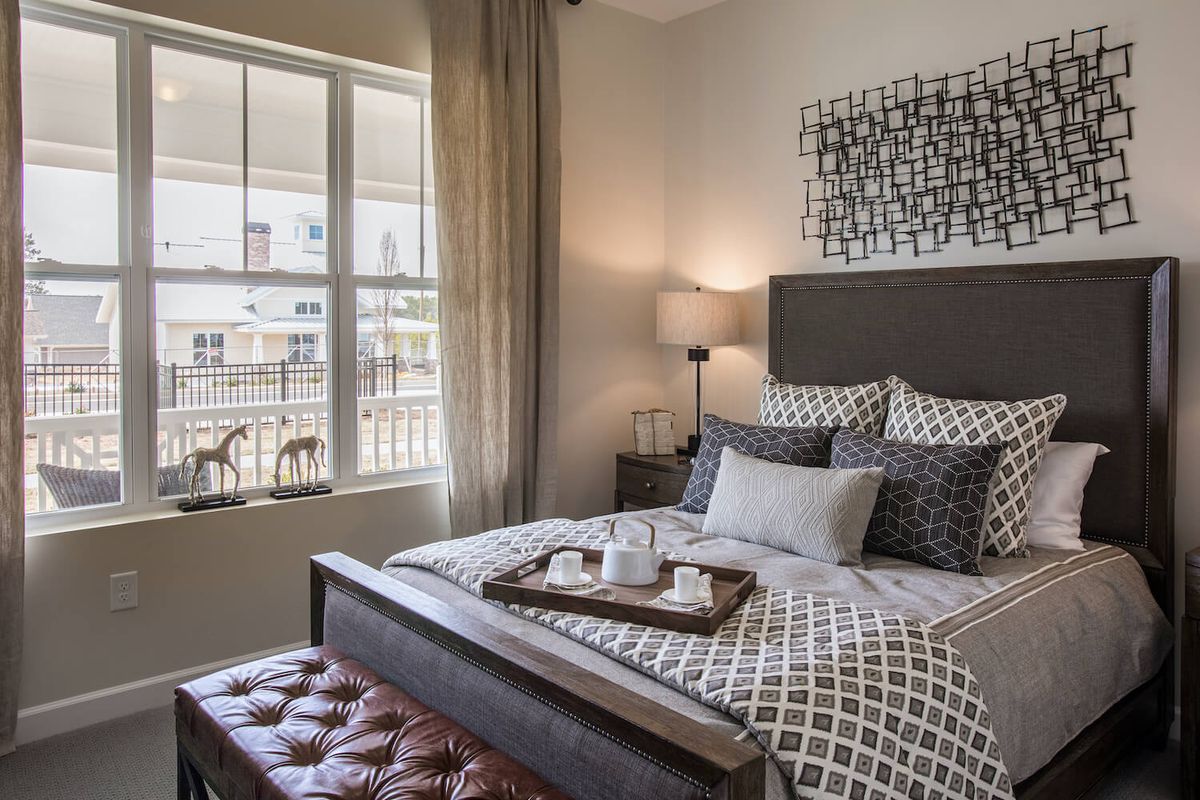 A stylish bedroom with a neatly made bed, decorative pillows, and a tray on top.