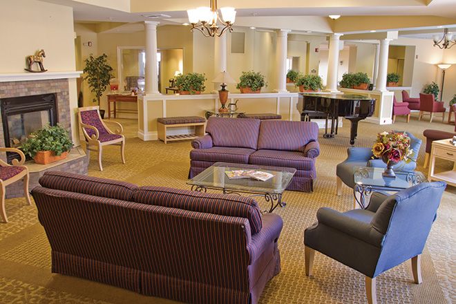 A luxurious living room with purple sofas and a grand piano.