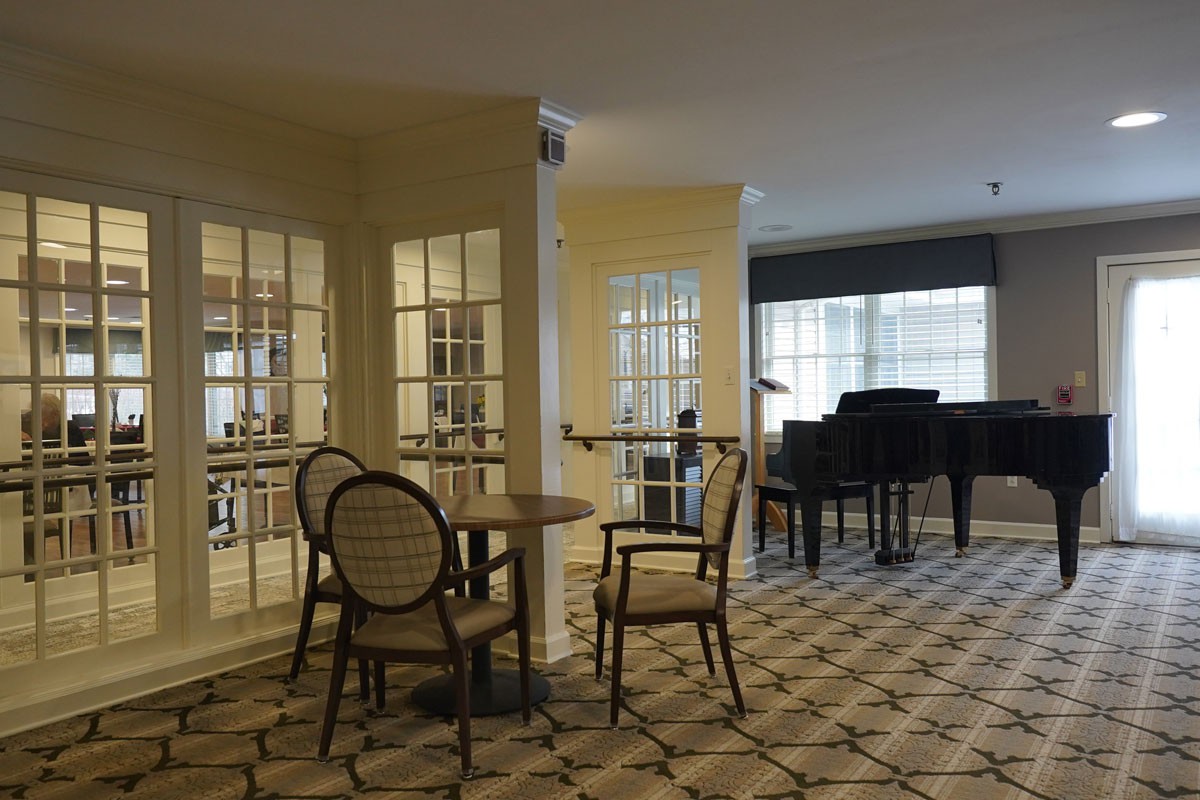 A cozy indoor setting with a piano, chairs, and a table.