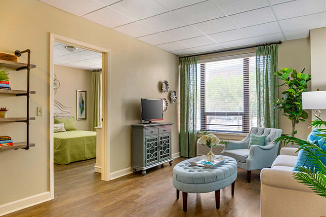 A modern apartment living room featuring comfortable seating and large windows.