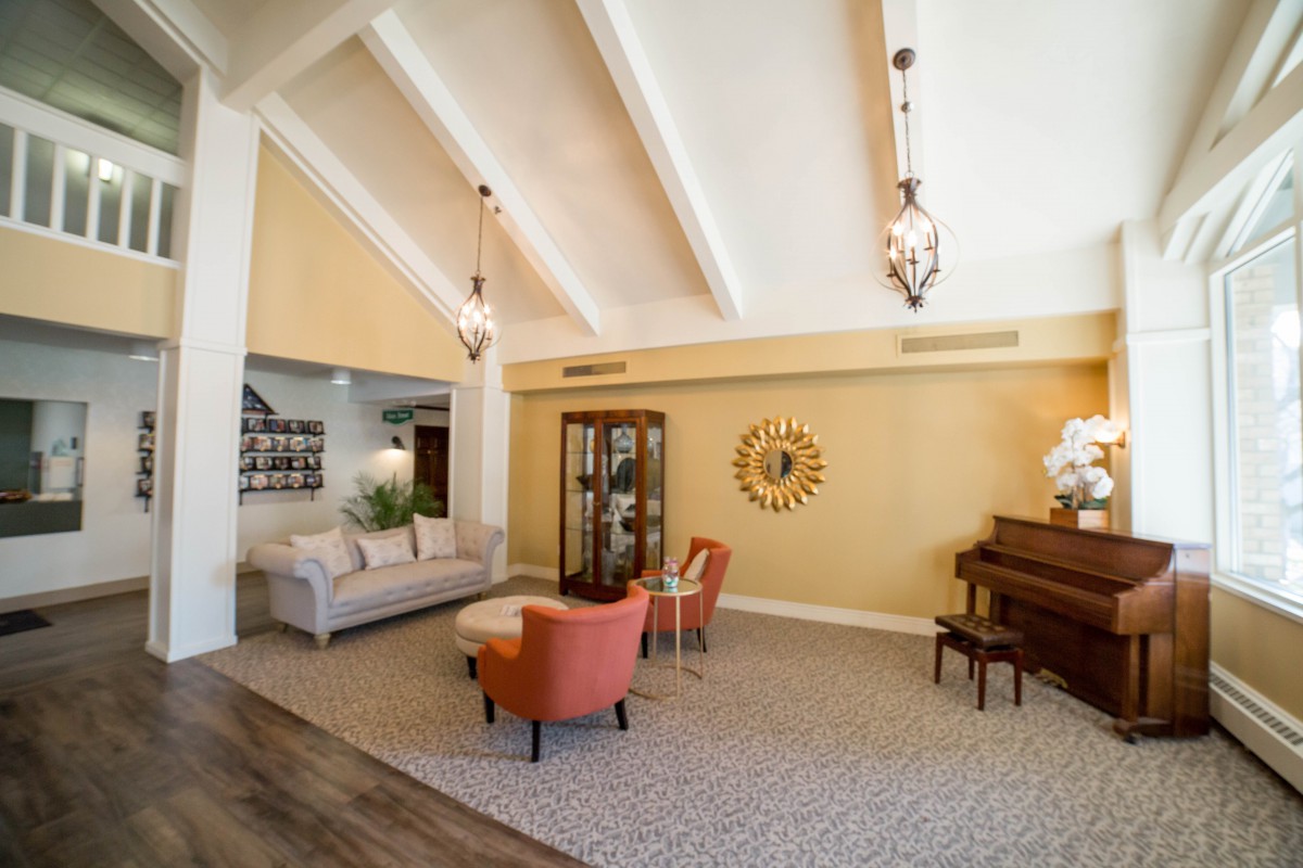 A cozy living room with vaulted ceilings, elegant lighting, and a piano.