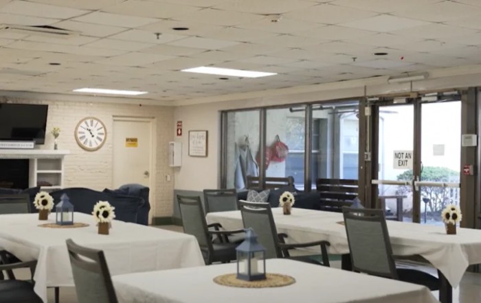 An indoor dining area with neatly arranged tables and chairs, a wall clock, and ceiling lights.