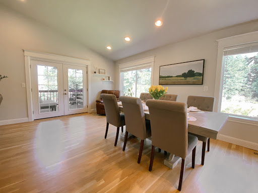A bright and inviting dining room featuring a modern table set for meals, surrounded by comfortable seating.