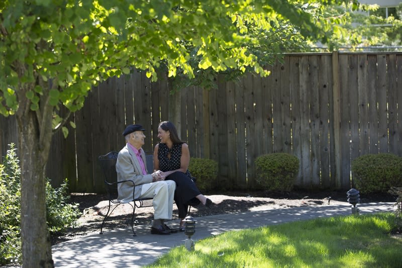 A couple sitting and talking in a garden on a sunny day.