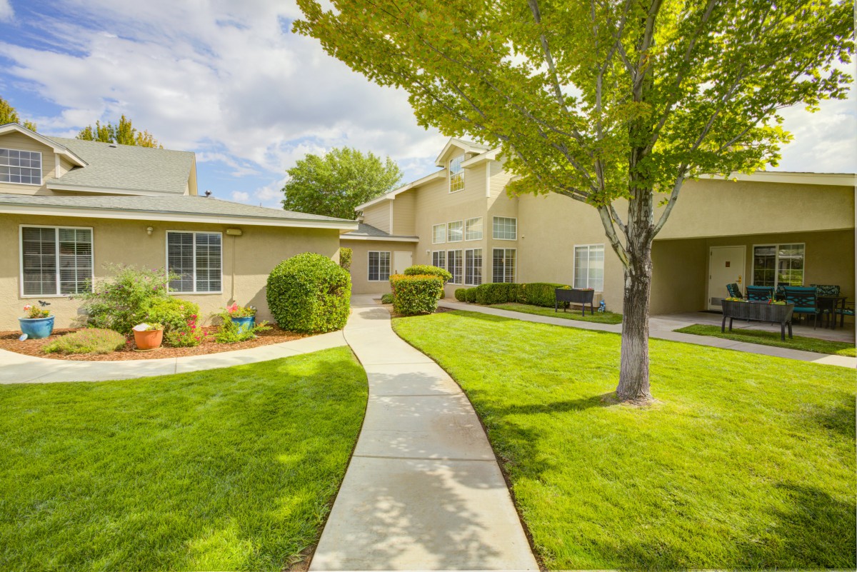A charming residential home with a well-manicured lawn and a winding pathway leading to the entrance.