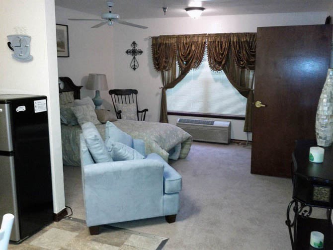 A cozy living room with a bed, armchair, and decorative curtains.