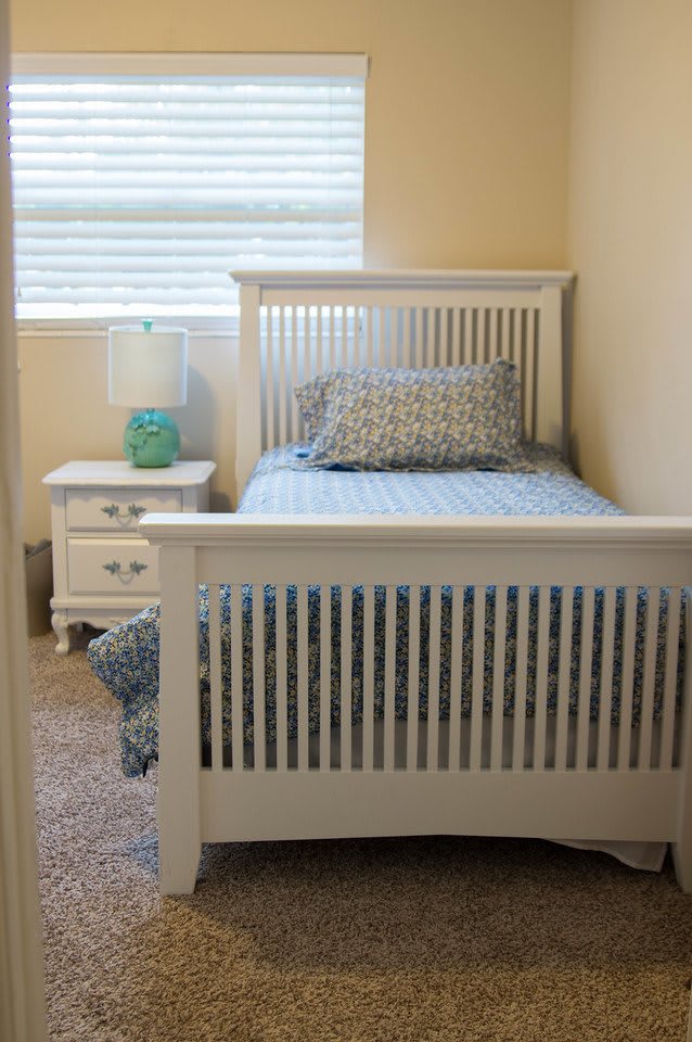 A cozy bedroom with a single bed, nightstand, and lamp.