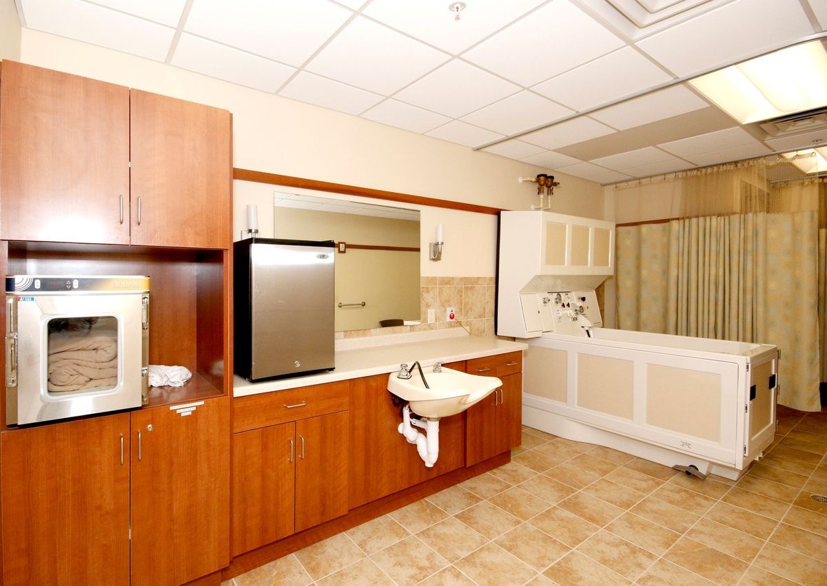 A spacious bathroom with a bathtub, sink, mirror, and wooden cabinets.
