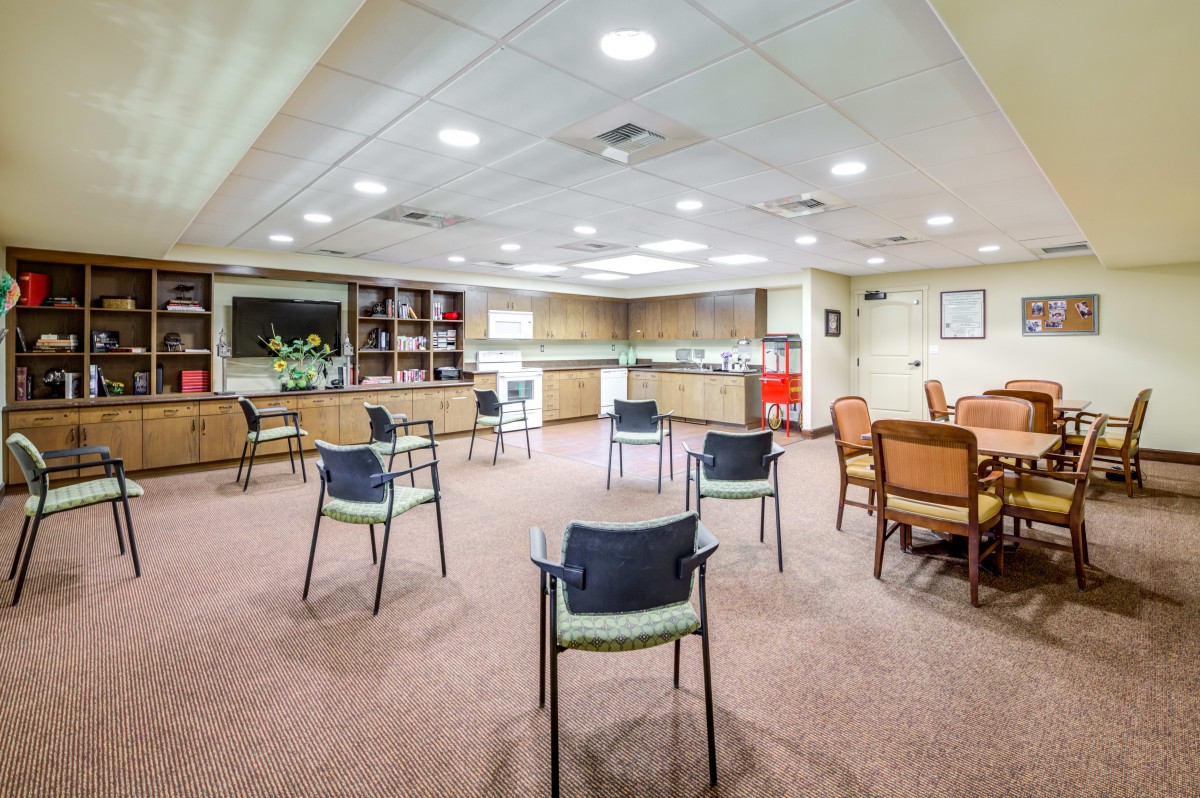 A spacious conference room with chairs arranged for a meeting, featuring bookshelves and bright indoor lighting.