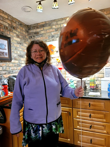 A cheerful individual holding a large balloon in a cozy indoor setting.