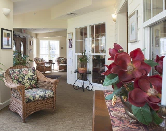 A cozy living room featuring wicker furniture and a floral arrangement.