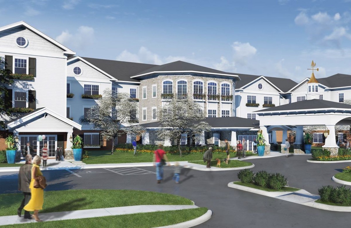A modern residential apartment complex with landscaped surroundings and people walking.