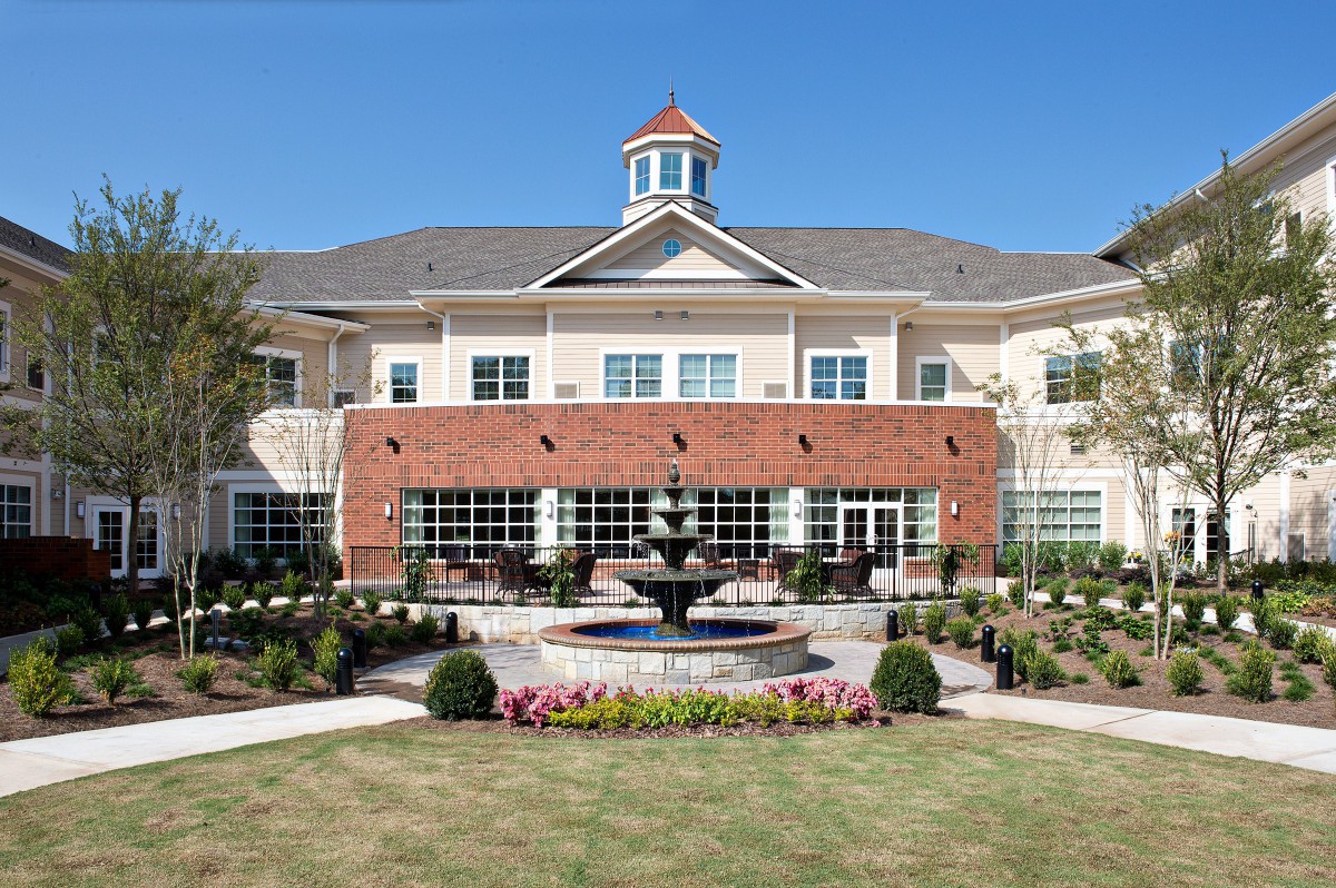 A symmetrical building with a central fountain and landscaped garden.
