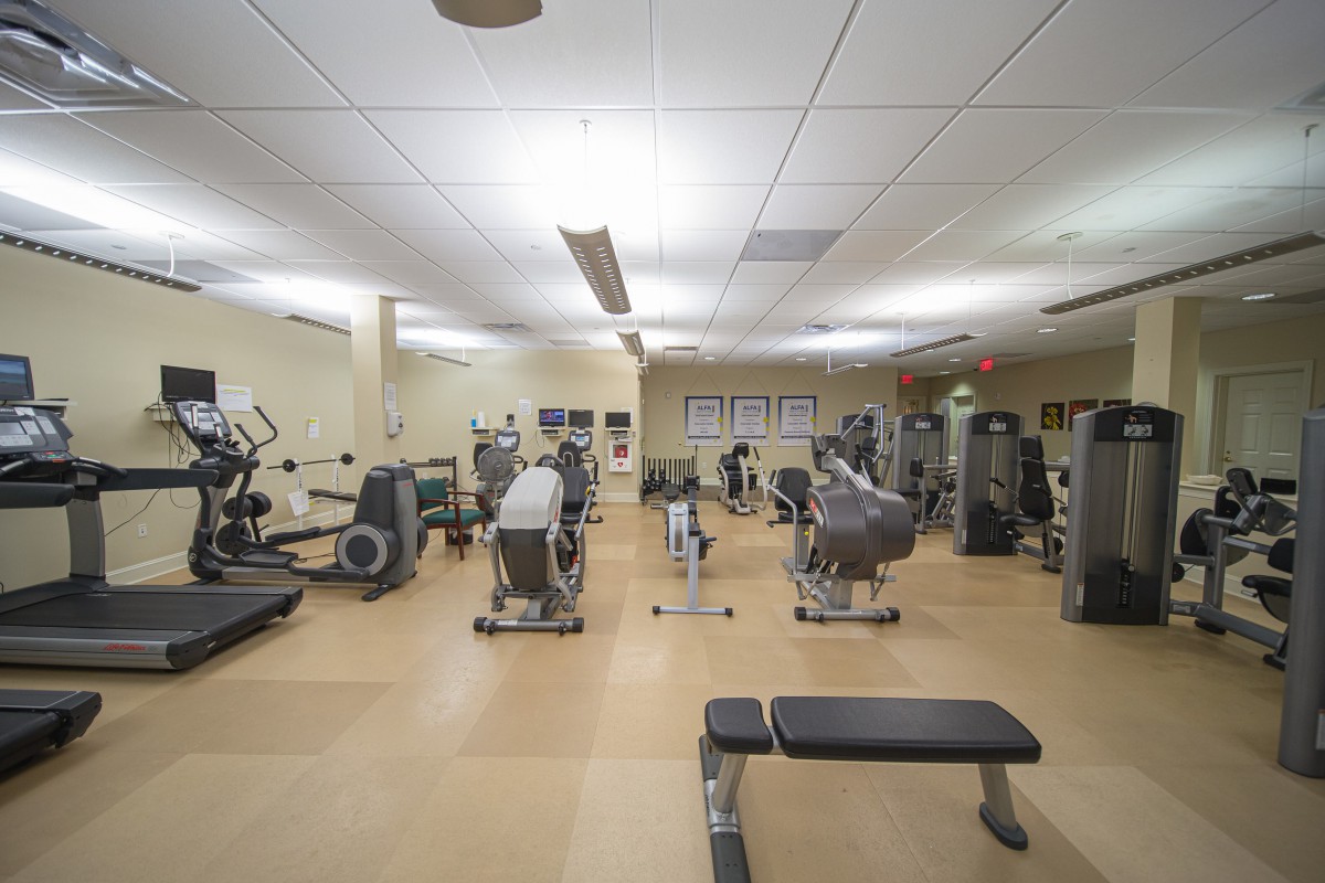 A well-equipped gym with various exercise machines and benches.