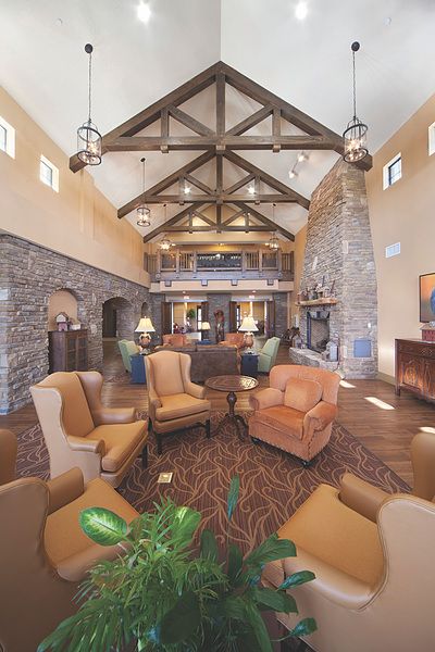 A spacious living room with high ceilings, wood beams, and a stone fireplace, featuring comfortable furniture and warm traditional decor.