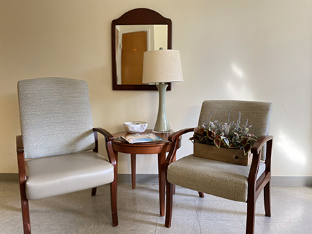 A cozy seating area featuring two chairs, a small table with a plant arrangement, and a lamp reflecting the warm ambiance of the room.
