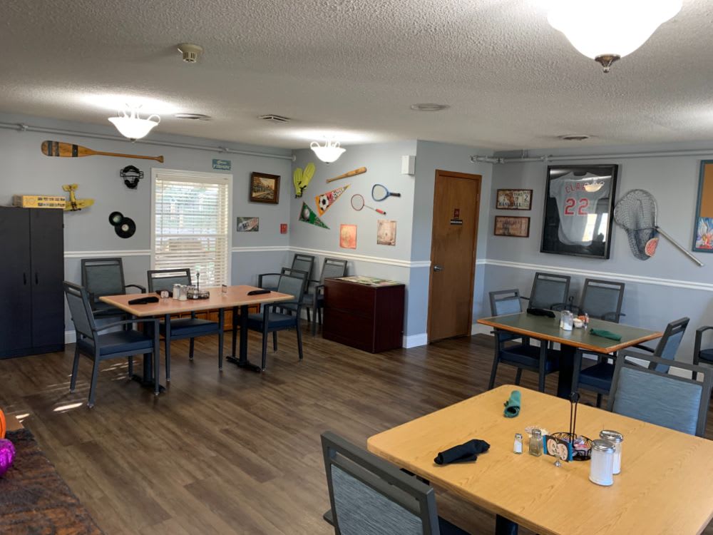 A cozy dining area featuring several tables and chairs, decorated with various artworks and memorabilia on the walls.