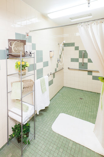 A well-designed bathroom featuring green tiles and accessibility features.