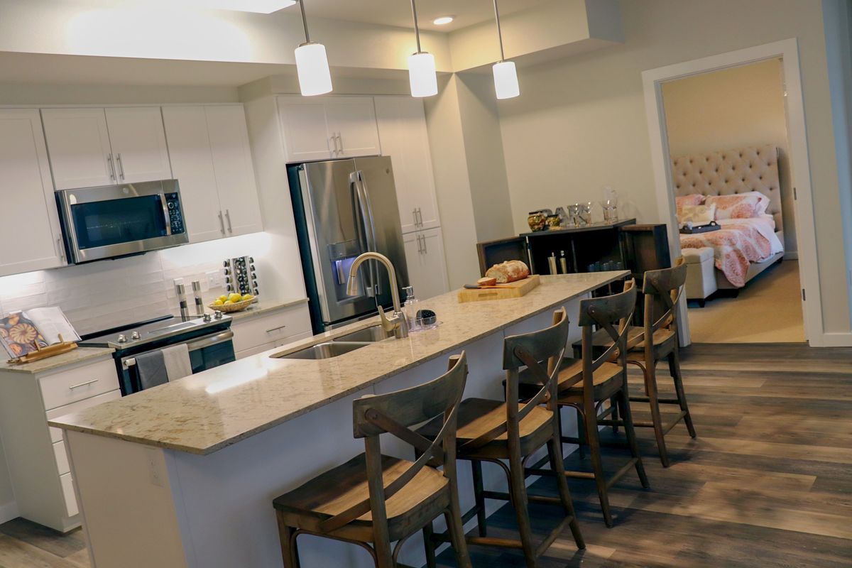 A modern kitchen featuring a central island with bar stools and pendant lighting.