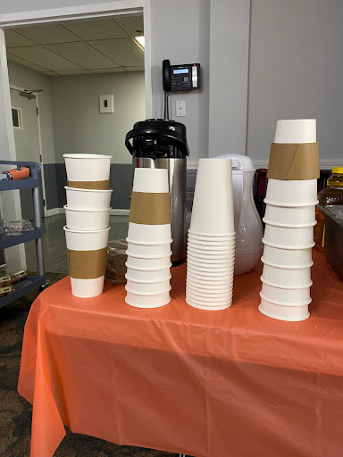 A neatly arranged display of stacked cups on an orange table, ready for a beverage service.