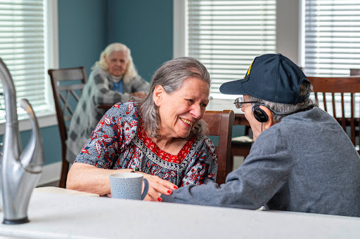 An elderly woman engages in a warm conversation with an older man, showcasing the joy of companionship in a community setting.