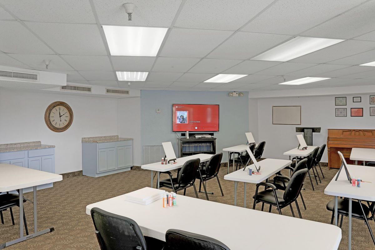 An empty classroom equipped with desks, chairs, and a projector screen.